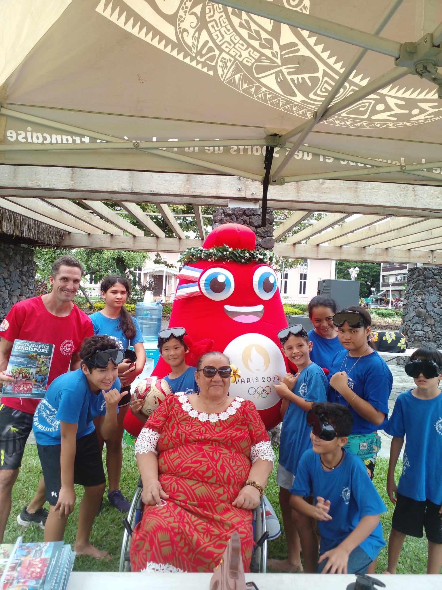 une photo de notre Présidente Henriette KAMIA en compagnie de Jérémie de la Fédération Polynésienne des Sports Adaptés et Handisport lors de la Fan Zone, avec les élèves de différentes écoles en découverte des activités proposées